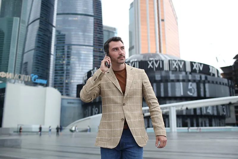 A confident businessman using a smartphone in a modern cityscape, symbolizing secure and professional business communication.